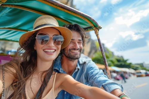 Joyful young couple takes a selfie while exploring the city in a tuk-tuk, showcasing fun and travel