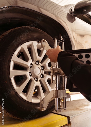 Auto mechanic installing sensor during suspension adjustment and automobile wheel alignment work at repair service station. Close up photo