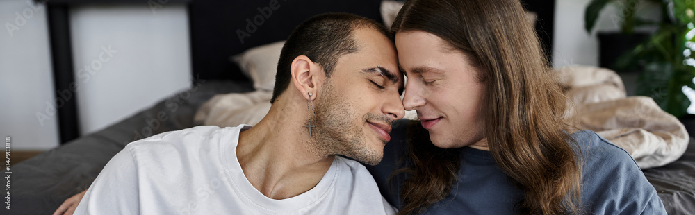 Fototapeta premium A young gay couple shares a tender moment in their bedroom, their foreheads touching as they close their eyes.