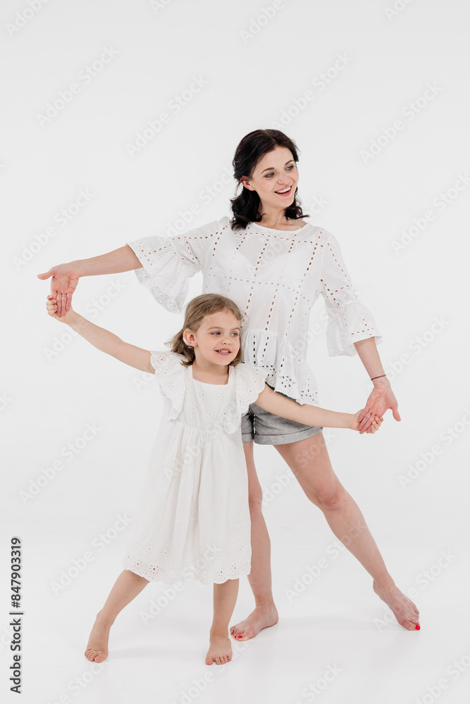 Happy mother and daughter playing and having fun on a white background. Concept of a happy family, motherhood, style and fashion. Happy mother and daughter playing and having fun on a white background. Concept of a happy family, motherhood, style and fashion.