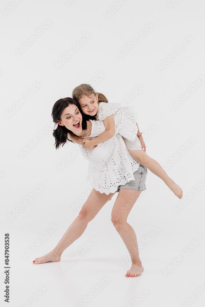 Happy mother and daughter playing and having fun on a white background. Concept of a happy family, motherhood, style and fashion. Happy mother and daughter playing and having fun on a white background. Concept of a happy family, motherhood, style and fashion.