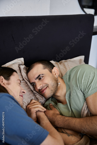 A young gay couple cuddles in bed, sharing a tender moment of love and affection.