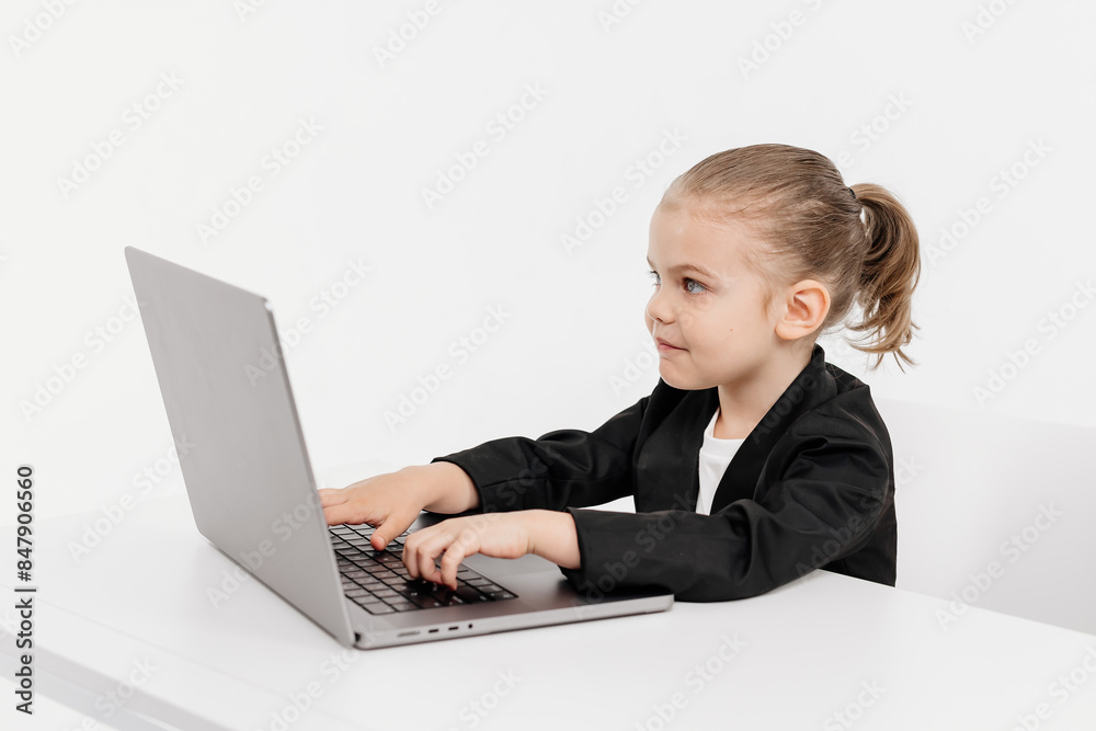 Little business girl child working or studying on a light background with a laptop. Modern online education, business and technology. Little business girl child working or studying on a light background with a laptop. Modern online education, business and technology.