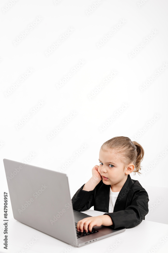 Close-up of a stylish business girl child studying at a laptop on an isolated white background. The concept of modern technology, business and education. Close-up of a stylish business girl child studying at a laptop on an isolated white background. The concept of modern technology, business and education.