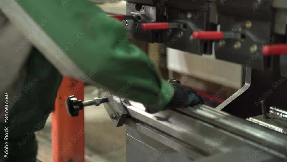 Worker in gloves makes a bend on a metal part using a CNC, close-up. Factory setting for working with metal. Worker in gloves makes a bend on a metal part using a CNC, close-up. Factory setting for working with metal.