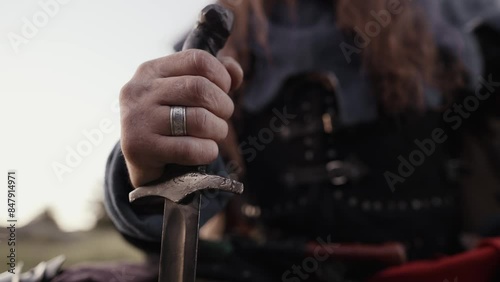 A warrior's hand holds the hilt of a sword