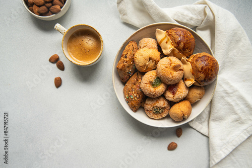 Variety of homemade Italian sweets typical for Sardinia region. Pardulas, amaretti, papassine and pizzicchi in bowl and espresso on white table. photo