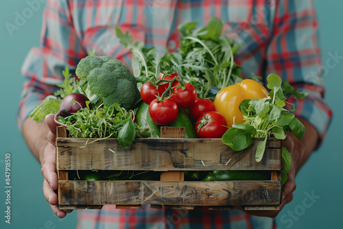 Cloes up on a farmer holding a wooden box full of fresh vegetables