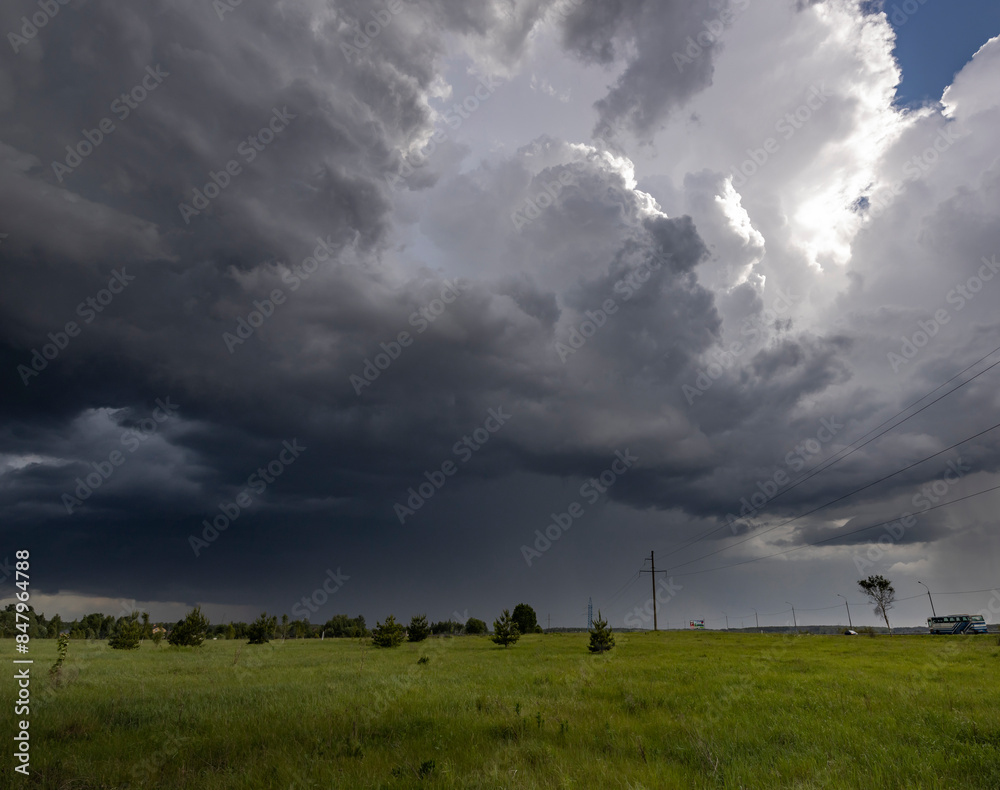 Fototapeta premium A picturesque view of a dramatic spring sky filled with dark, ominous clouds over a grassy field.