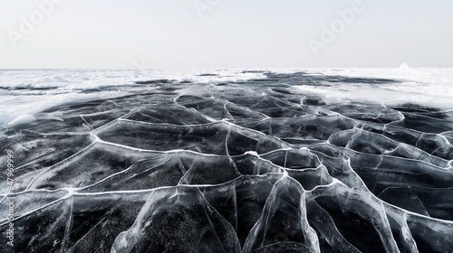 Black ice with natural cracking patterns, viewed up close under a clear winter sky. photo