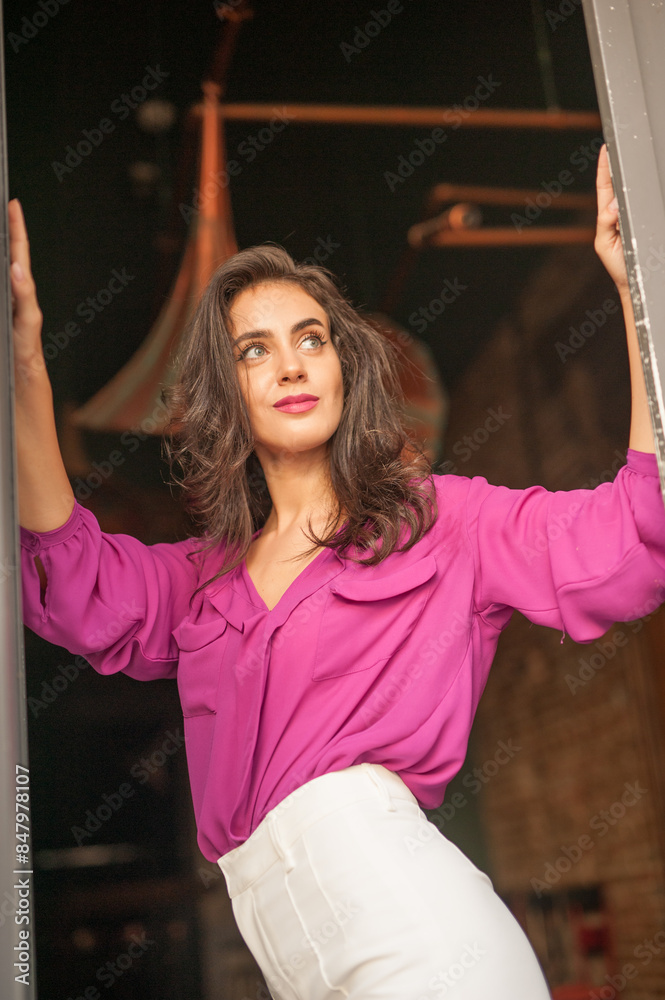 Beautiful young brunette woman in a purple blouse and white pants posing outdoor. Portrait of a beautiful young brunette woman with long hair posing fashion