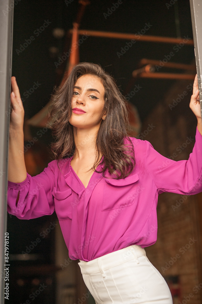 Beautiful young brunette woman in a purple blouse and white pants posing outdoor. Portrait of a beautiful young brunette woman with long hair posing fashion