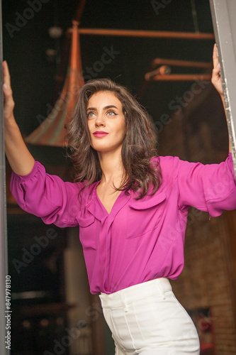 Beautiful young brunette woman in a purple blouse and white pants posing outdoor. Portrait of a beautiful young brunette woman with long hair posing fashion