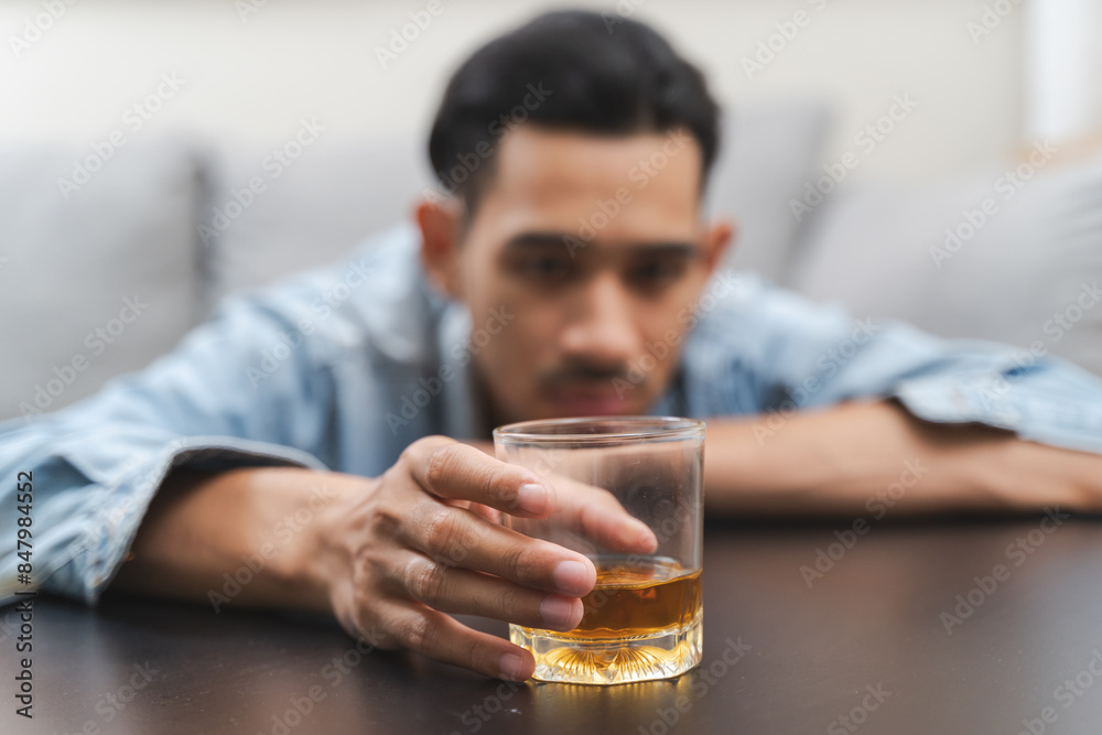 melancholy young Asian man drinks alcoholic whisky alone at home feeling dizzy after drunk melancholy young Asian man drinks alcoholic whisky alone at home feeling dizzy after drunk