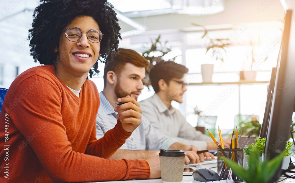 Love my job. Cheerful african american guy smiling at camera, sitting at modern coworking office, free space Love my job. Cheerful african american guy smiling at camera, sitting at modern coworking office, free space