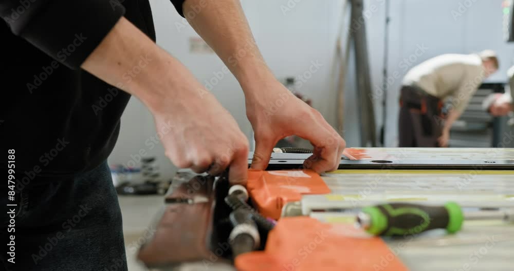 A close-up of a technician's hands working on the repair of an electric car battery pack in a modern workshop setting. Technician Repairing Electric Car Battery Pack in Workshop. Electric car. A close-up of a technician's hands working on the repair of an electric car battery pack in a modern workshop setting. Technician Repairing Electric Car Battery Pack in Workshop. Electric car.