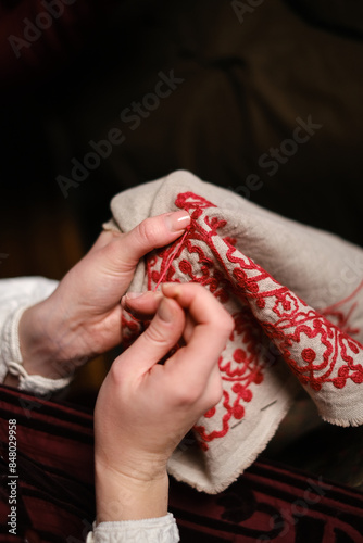 A close-up of a woman’s hands skillfully embroidering traditional Ukrainian patterns. photo