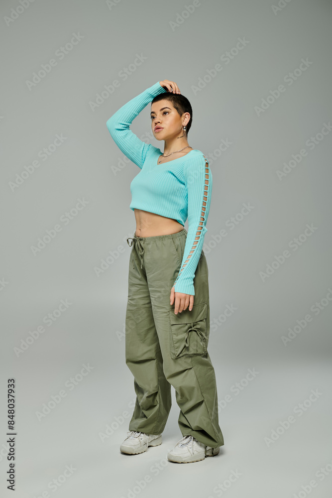 Young woman with short hair strikes a pose in trendy casual outfit against a grey backdrop. Young woman with short hair strikes a pose in trendy casual outfit against a grey backdrop.