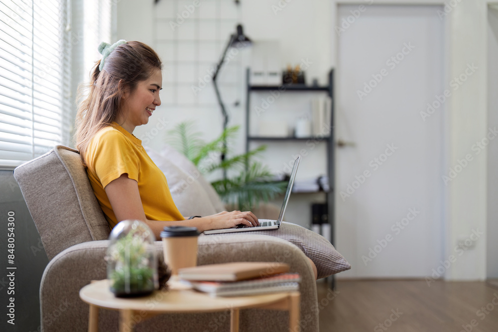 Young Woman Enjoying Social Media on Laptop at Home in Cozy Living Room with Modern Decor and Natural Light Young Woman Enjoying Social Media on Laptop at Home in Cozy Living Room with Modern Decor and Natural Light