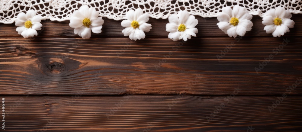 Obraz premium Top view of the process of hand crocheting of lace from white cotton yarn and a sprig of white flowers on a wooden background Hobbies and handicrafts in the summer DIY concept Flat lay close up