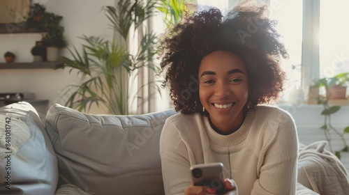 Smiling woman with cell phone in bright living room, capturing a happy moment in a photoreal commercial setting. cheerful scene highlighting modern technology and relaxed home lifestyle generative ai photo