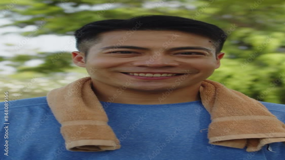 Vertical portrait of young sportsman using towel to wipe his face and smiling at camera after morning workout outdoors Vertical portrait of young sportsman using towel to wipe his face and smiling at camera after morning workout outdoors
