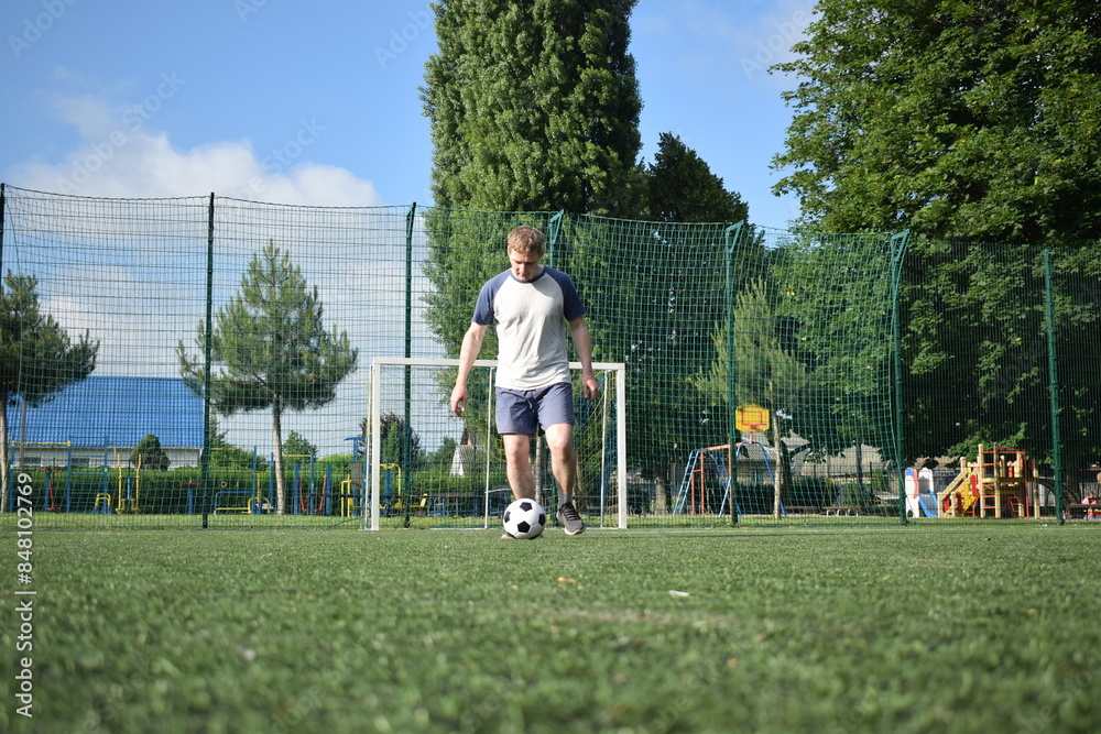 A young man in sportswear is playing soccer, training on a football pitch in the morning. Dedication and passion for the sport, the essence of morning exercise and practice outdoors A young man in sportswear is playing soccer, training on a football pitch in the morning. Dedication and passion for the sport, the essence of morning exercise and practice outdoors