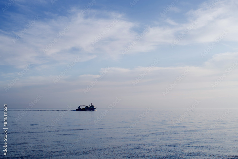 Fishing boat on the horizon against the background of a blue calm sea and a cloudy sky on a summer evening Fishing boat on the horizon against the background of a blue calm sea and a cloudy sky on a summer evening