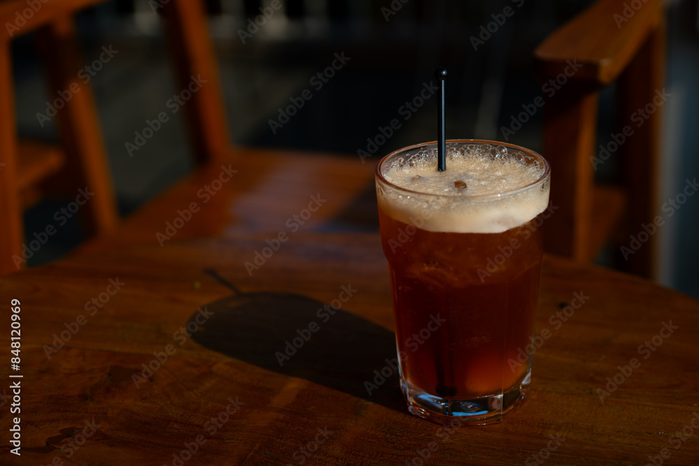 iced peach tea refreshment drink served on tall transparent glass, over wooden table surface, in cafe environment iced peach tea refreshment drink served on tall transparent glass, over wooden table surface, in cafe environment