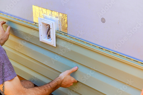 Vinyl plastic siding panels are installed on wall facade of new building by an employee photo