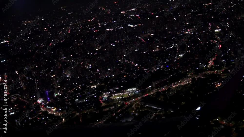 View from the plane window of the lights of a glowing city at night. Flight over the metropolis at night on an airplane view from the wing window. Aircraft takeoff and climb