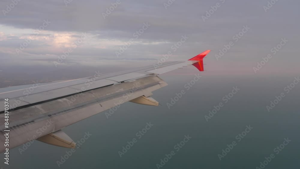 Airplane wing with sun through clouds and the sea in a background. Seascape, view from the porthole. Travel concept Airplane wing with sun through clouds and the sea in a background. Seascape, view from the porthole. Travel concept
