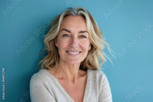 radiant confidence smiling middleaged woman looking directly at camera positive studio portrait on blue