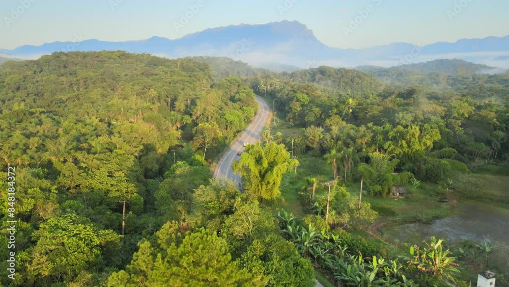 Voo sobre mata atlântica e estrada de Antonina com pico Marumbi ao fundo na região de Morretes no Paraná