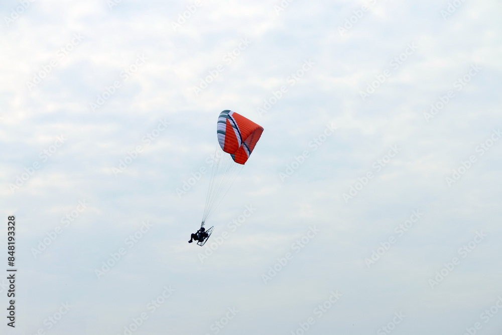 Paramotor vehicle flying over blue sky, Powered paraglider Paramotor vehicle flying over blue sky, Powered paraglider