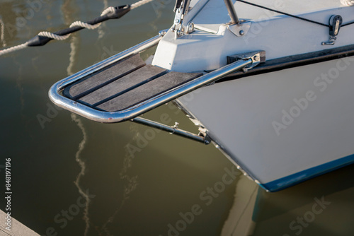 Photos Wooden bowsprit on the moored sailboat in the harbor, calm water in marina