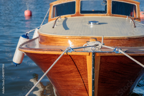 White rope tied to the mooring cleat of a wooden sailboat, sunny light photo