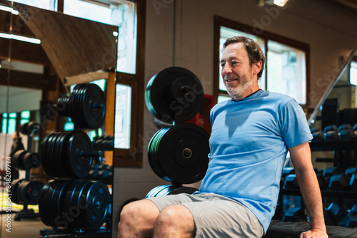 A man in a blue shirt is doing tricep dips on a gym bench