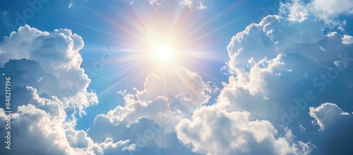 Bright midday sun shining on fluffy clouds in the blue sky, creating a wide and radiant scene.