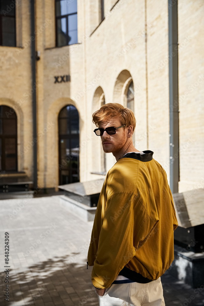 Young red-haired man in yellow jacket and white pants strolling through city streets. Young red-haired man in yellow jacket and white pants strolling through city streets.
