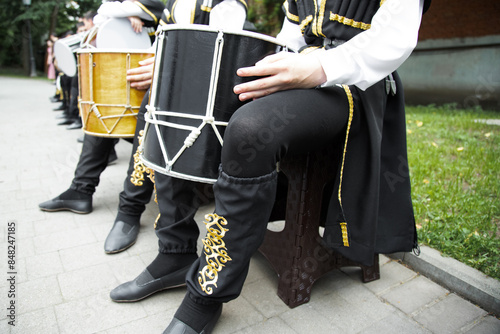 caucasian man in a ethnic costume sits on a chair and plays the drum . Drums of the peoples of the Caucasus photo