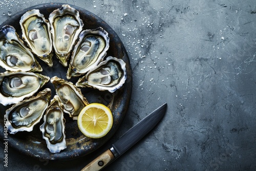 Fresh oysters on a dark plate with a lemon wedge and a knife