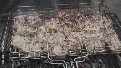 Meat kebab is on a grill grate and burning barbecue coals under it close up. Camera moving right close up along the grill grate. photo