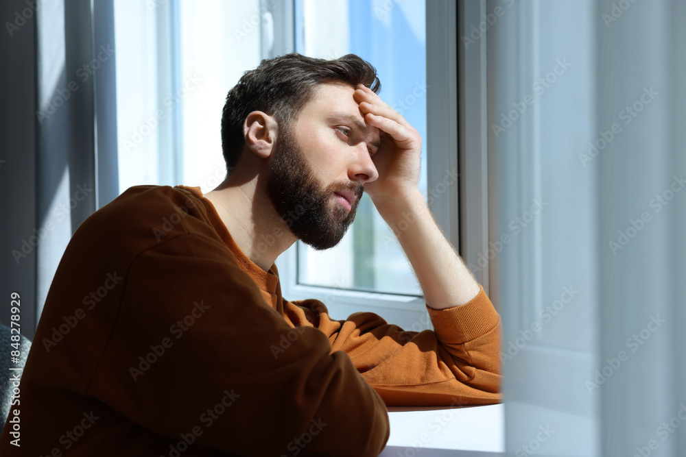 Loneliness concept. Sad man near window at home Loneliness concept. Sad man near window at home