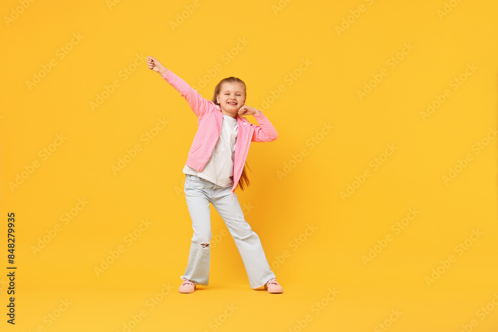 Cute little girl dancing on yellow background, space for text Cute little girl dancing on yellow background, space for text