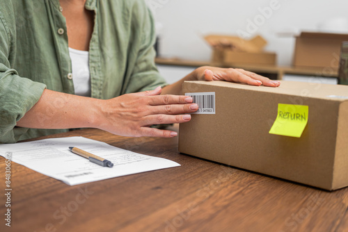 Obraz na płótnie Hands of female consumer stick barcode on cardboard box with yellow sticker with
