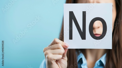 Person holding a sign with 'No' text, concept of refusal, rejection, or denial, blue background.