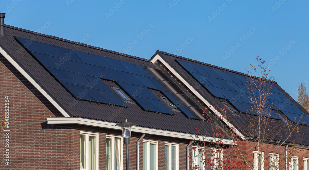 Fototapeta premium Solar panels on the roofs of houses on a sunny day, blue sky 