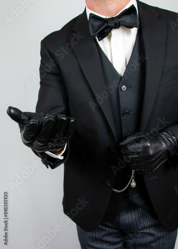 Portrait of Gentleman in Dark Suit and Bowtie Offering Helping Hand. Vintage Style of Classic British Butler.