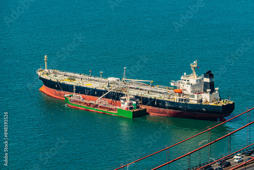 Oil tanker receiving fuel from bunkering tanker in the port